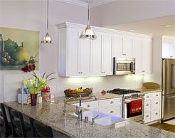 Remodeled kitchen with white cabinetry and pendant lighting