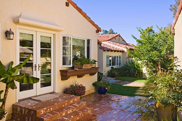 Yellow stucco cottage with French doors and a window box